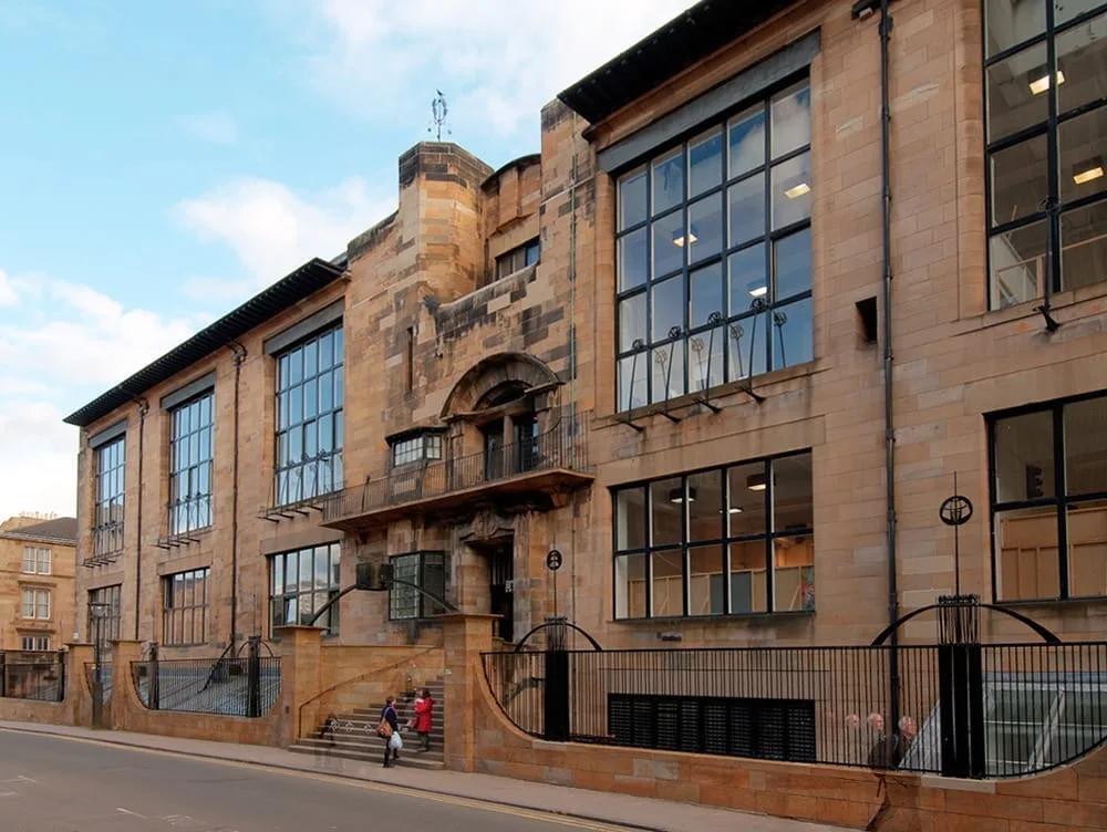 Fachada norte da Escola de Arte de Glasgow, em arenito, com grandes janelas de estúdio e gradis de ferro trabalhado