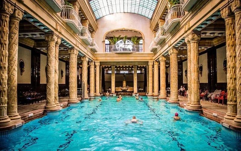 Piscina coberta das Termas Gellért com colunas ornamentadas e teto abobadado de vidro