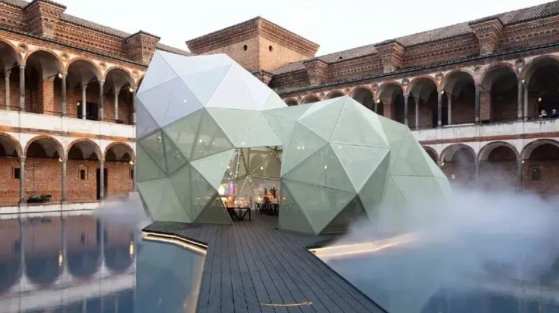Pavilhão geométrico translúcido cercado de água e névoa no Cortile della Farmacia da Università degli Studi di Milano