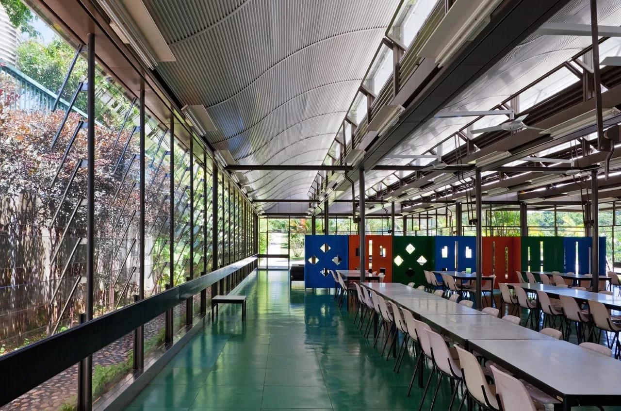 Refeitório do Hospital Sarah de Salvador, com cobertura curva, fachada envidraçada para o jardim e painéis coloridos