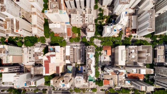 Vista aérea de quarteirões com prédios residenciais e árvores em uma área urbana densa