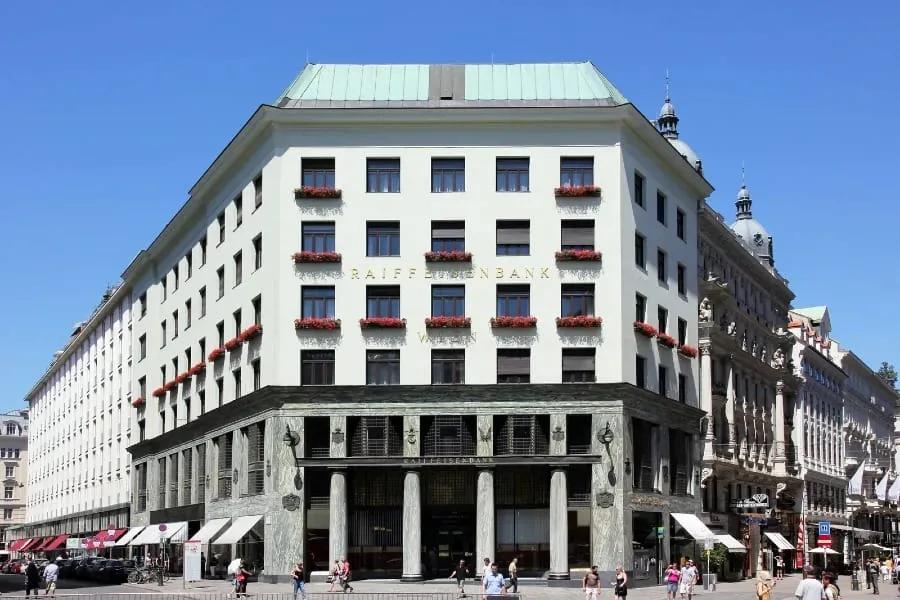 Looshaus, edifício de esquina com base revestida de mármore e colunas e andares superiores brancos e lisos com floreiras nas janelas