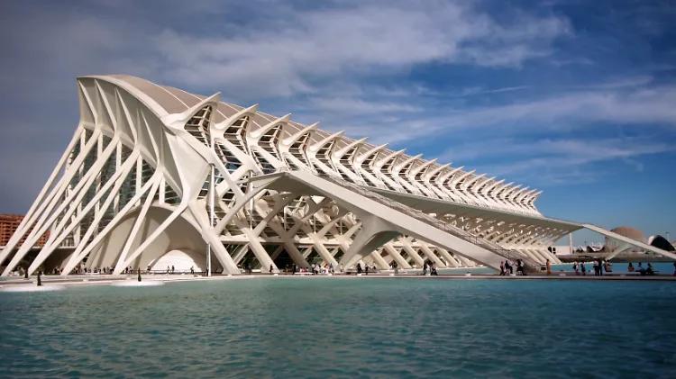 Fachada do Museu de les Ciències com estrutura branca de costelas repetidas refletida na água