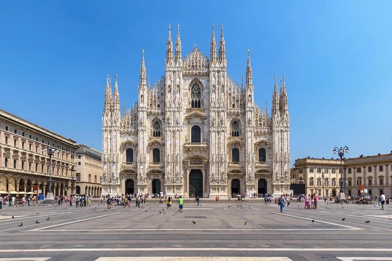 Duomo de Milão Fachada gótica branca do Duomo de Milão, com dezenas de pináculos e agulhas, vista da praça