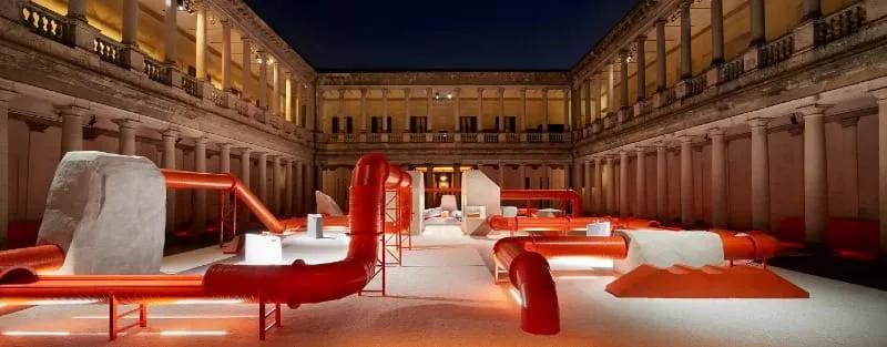 Terminal 02, de Samuel Ross para Kohler Tubulações laranja da instalação Terminal 02 atravessando o pátio iluminado do Palazzo del Senato