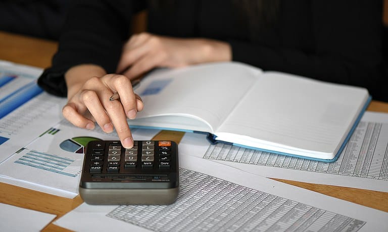 Pessoa calculando dados de planilha de gastos.