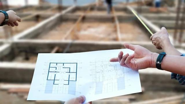 Arquiteto conferindo canteiro de obra com planta do projeto impresso em mãos.