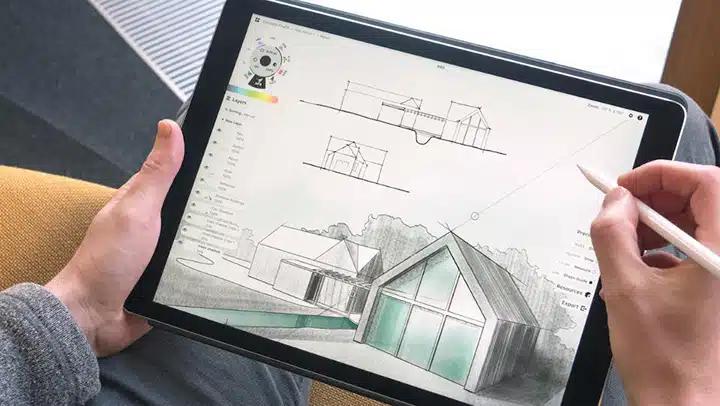 Mãos desenhando com caneta no tablet a perspectiva de uma casa, com vistas em elevação no alto da tela