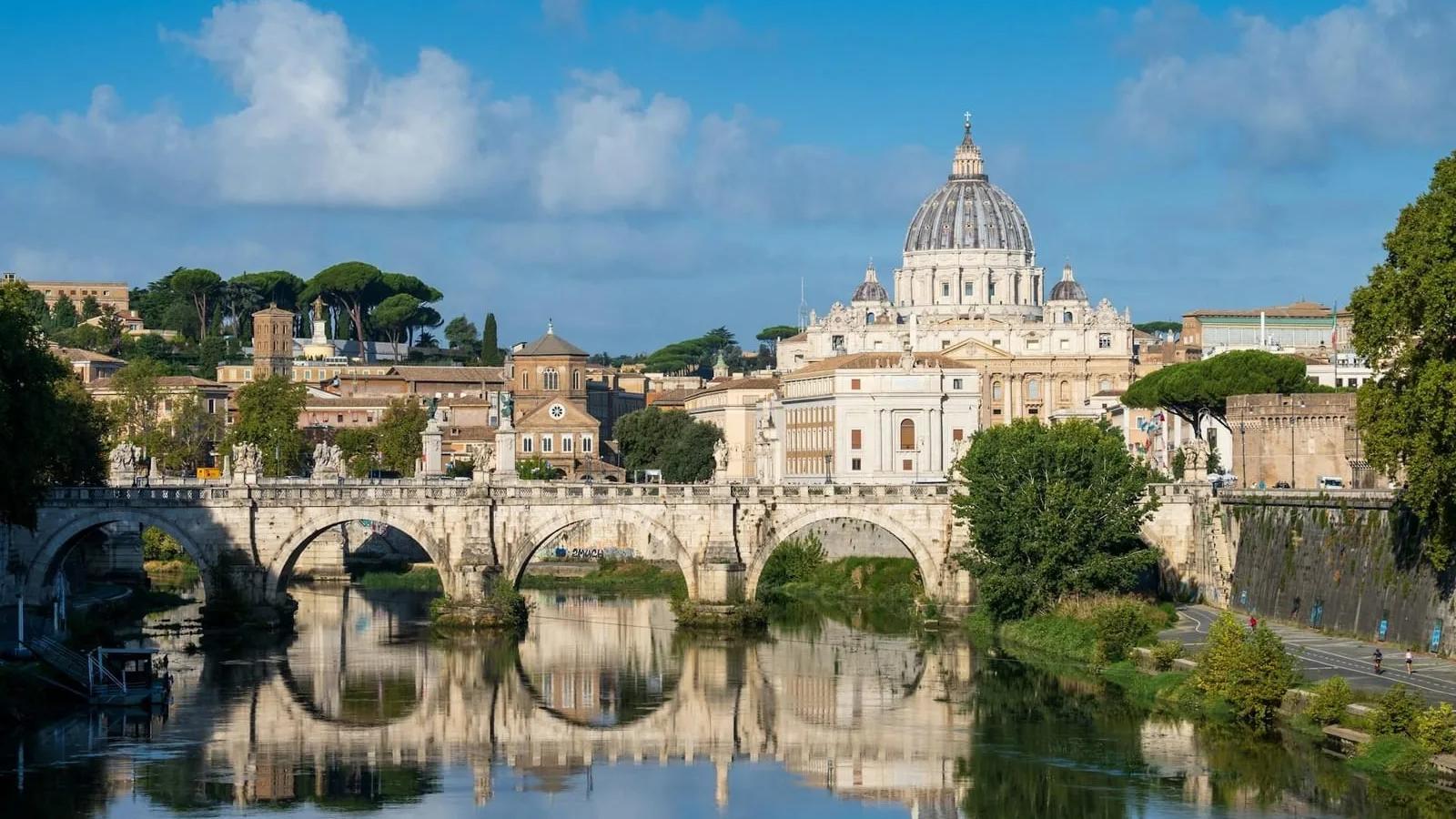 Arquitetura barroca Basílica de São Pedro vista da margem do rio Tibre, em Roma, com ponte de pedra refletida na água