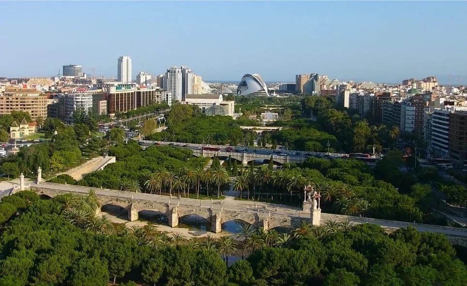 Ponte histórica sobre o antigo leito Vista do Jardim do Túria com uma ponte de pedra em arcos sobre o antigo leito arborizado e prédios ao fundo