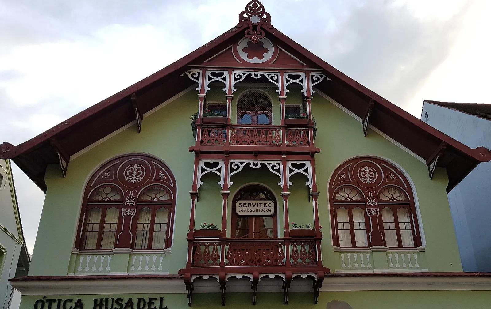 Casa Husadel, Blumenau Casa Husadel, em Blumenau: fachada verde de estilo germânico com varandas e ornamentos de madeira vermelha