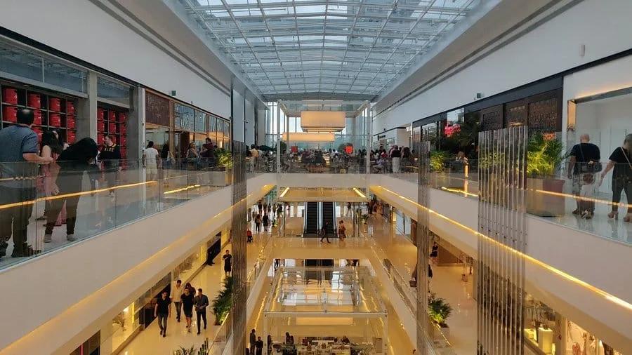 Corredores e pisos de um shopping center Corredores de um shopping em vários pisos com claraboia e pessoas caminhando