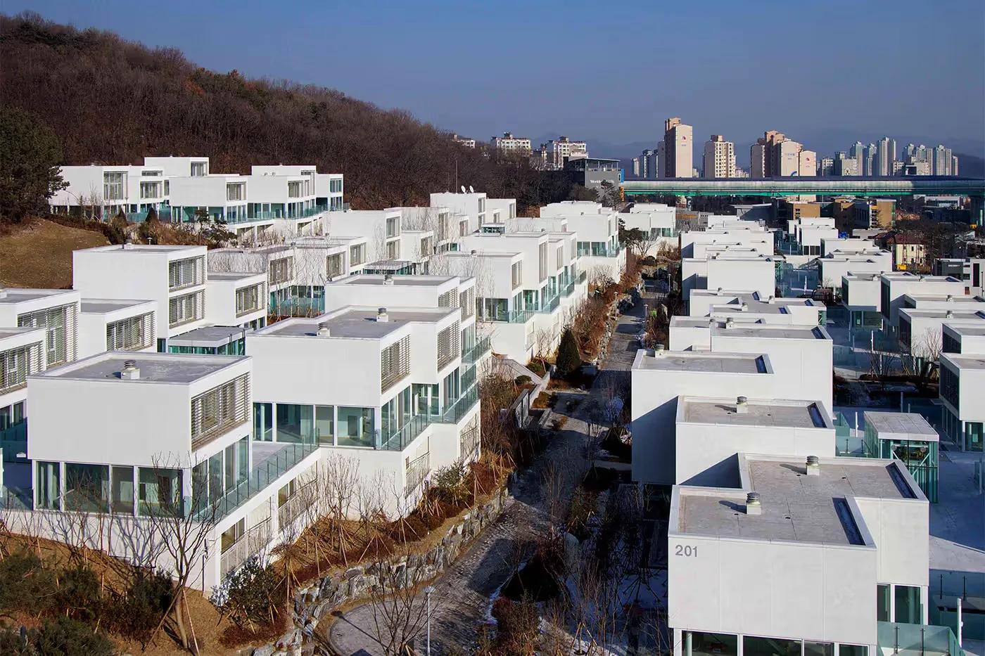 Pangyo Housing, Coreia do Sul Conjunto Pangyo Housing, na Coreia do Sul, com blocos baixos de fachadas envidraçadas e um deck comum elevado