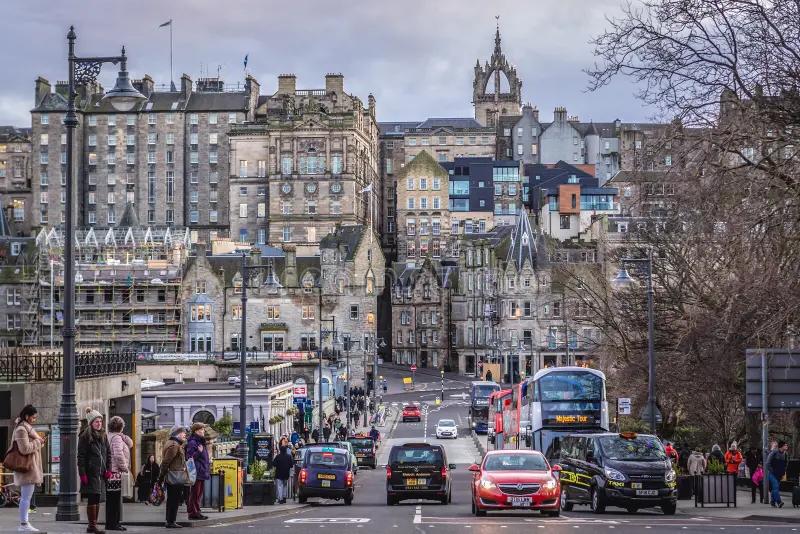 Waverley Bridge com carros e ônibus, e ao fundo a silhueta da Cidade Velha com prédios de pedra em vários níveis e uma torre