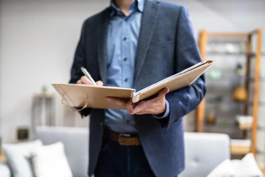 Homem representando perito avaliador com caderno fazendo anotações.