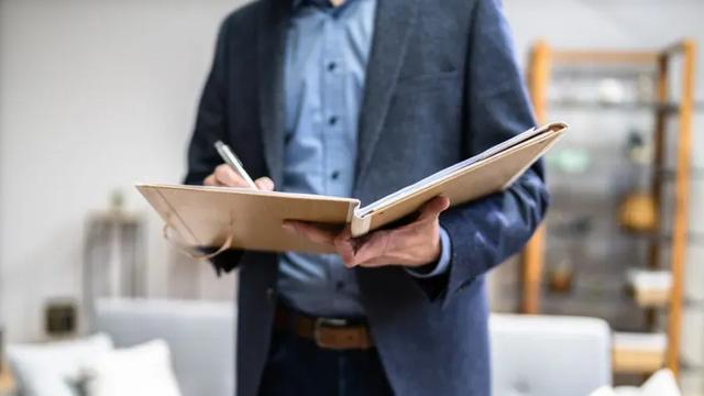 Homem representando perito avaliador com caderno fazendo anotações.