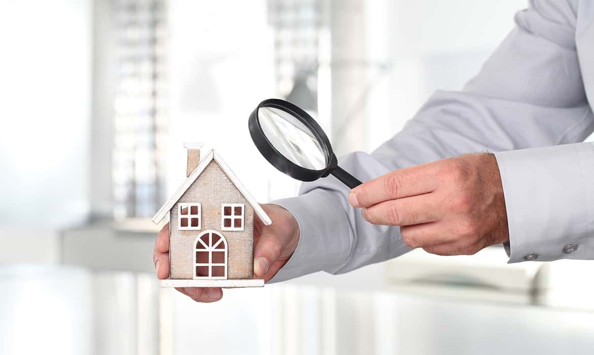 Casa sendo observada por lupa como analogia ao processo de avaliação imobiliária.