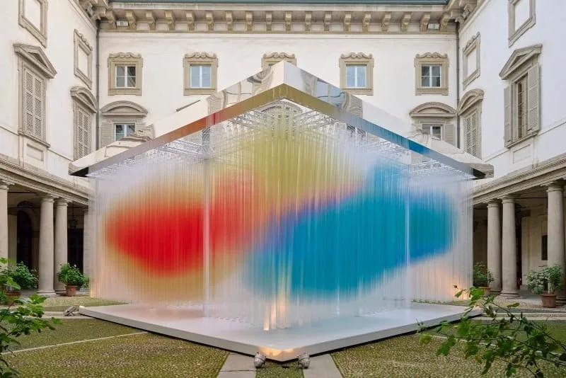 Cubo de tubos de tecido translúcido com degradê do azul ao vermelho no pátio do Palazzo Litta