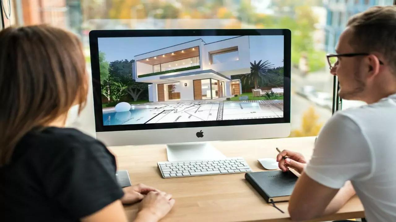 Duas pessoas diante de um monitor que mostra o render de uma casa moderna com piscina