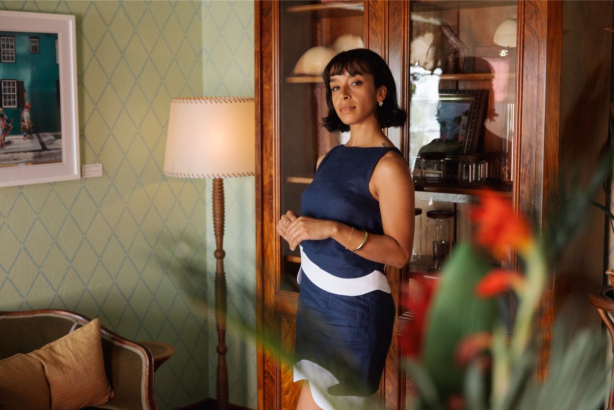 Model in a navy linen set standing by a floor lamp in a wallpapered sitting room