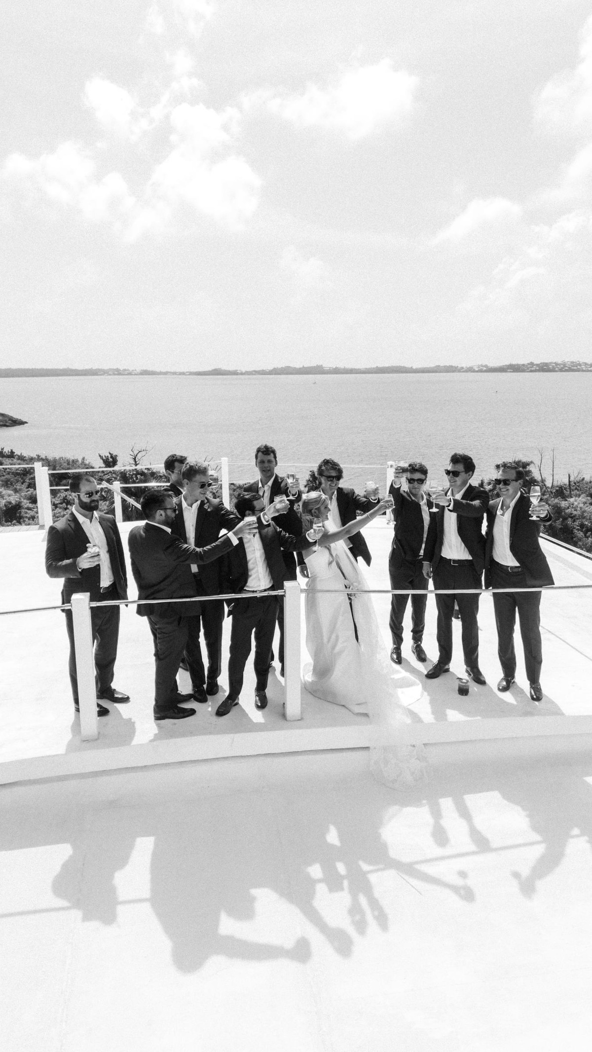 Groomsmen gather around Paige on the rooftop terrace on Hawkins Island, Bermuda, black and white