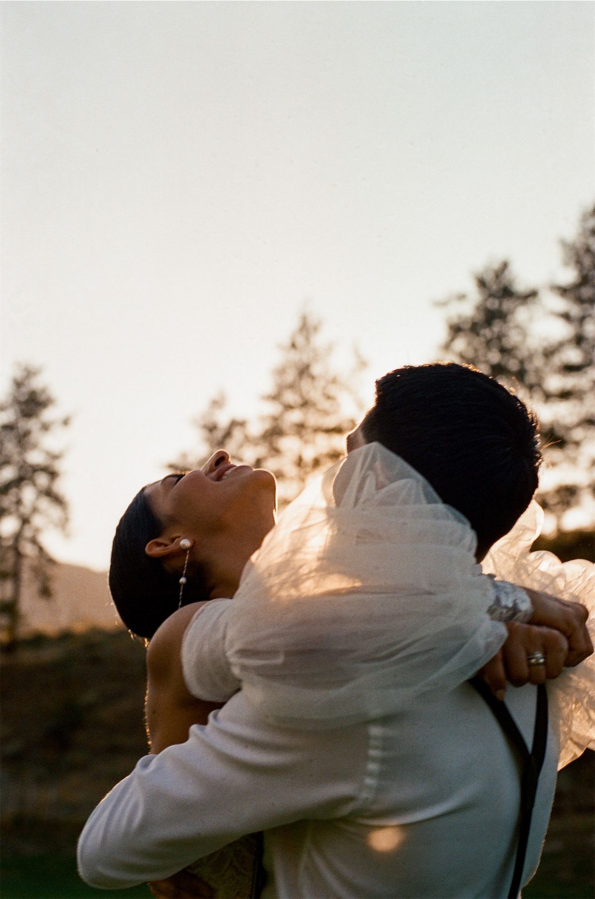 Groom lifting his laughing bride off the ground at golden hour in the hills