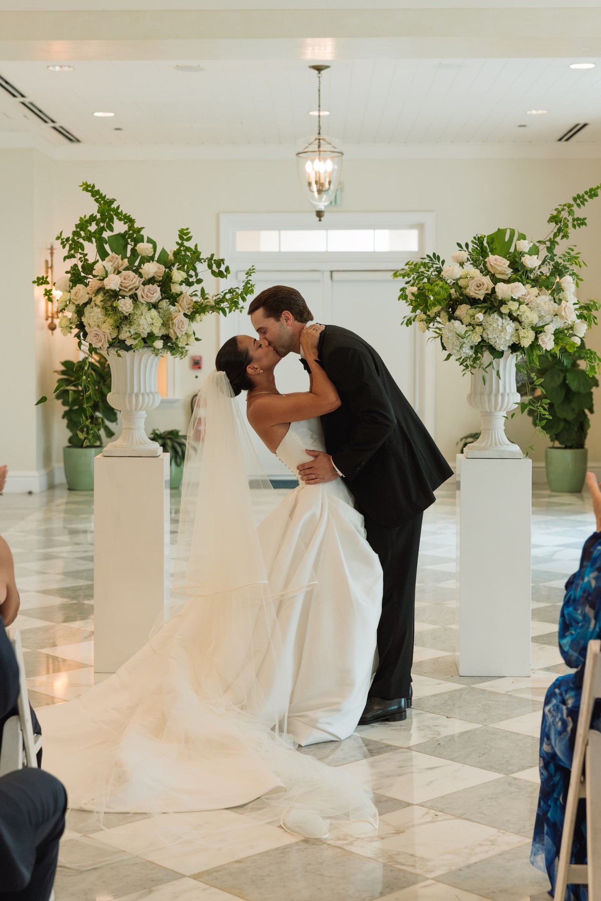 Couple's first kiss between tall floral urns in the ceremony room at Rosewood Bermuda
