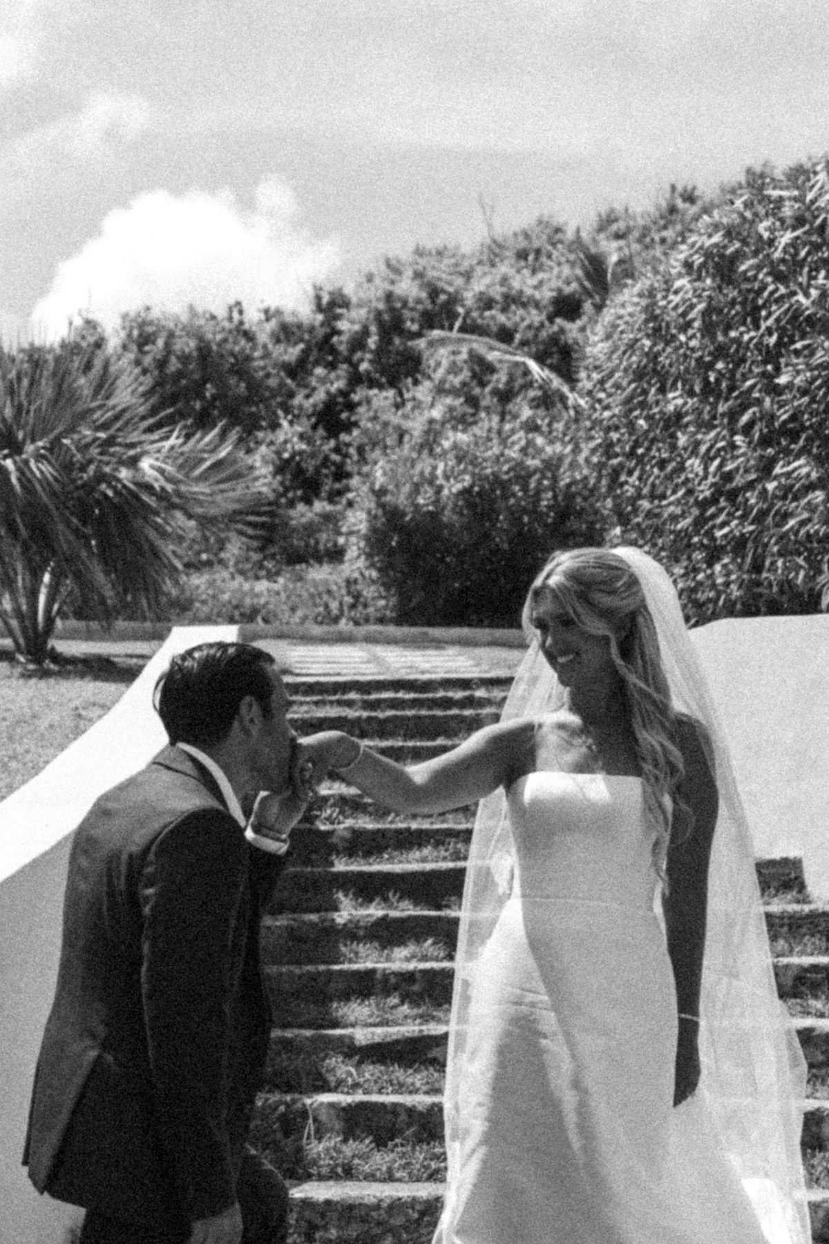 Cam kisses Paige's hand on the stone steps on Hawkins Island, Bermuda, black and white