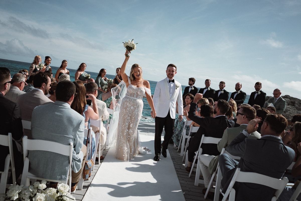 Joyful bride and groom recessional with raised bouquet at Bermuda wedding ceremony