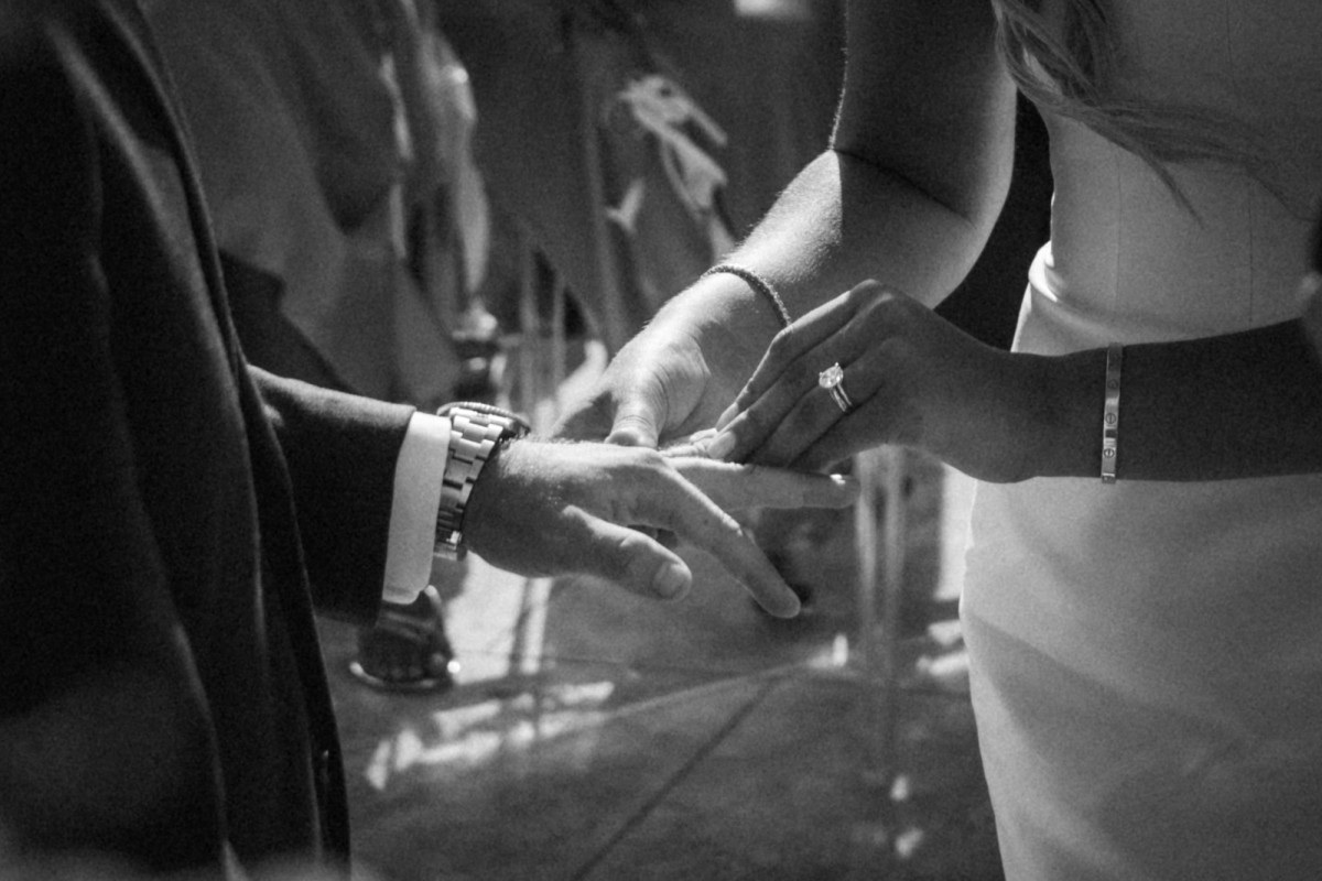 Cam slides the ring onto Paige's finger on Hawkins Island, Bermuda, black and white
