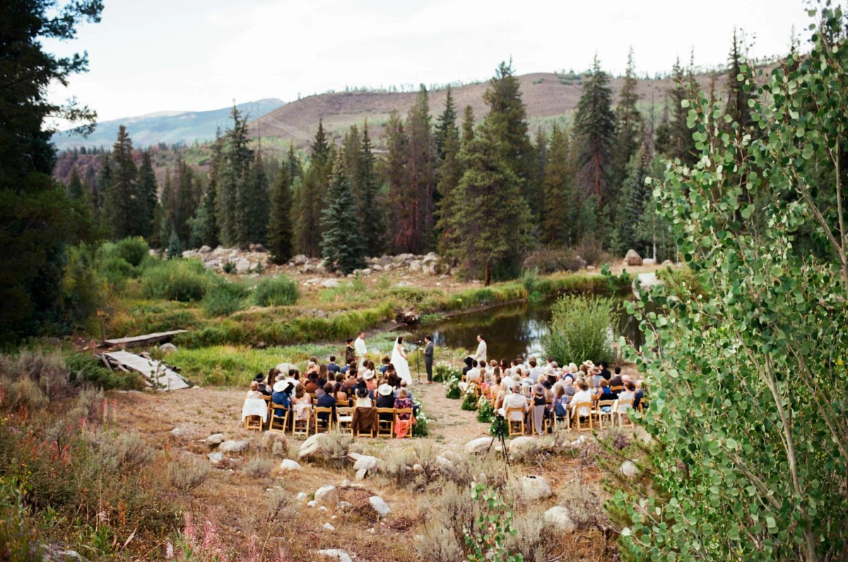 Guests seated around the ceremony circle beside the pond, shot on film at a mountain ranch among the aspens