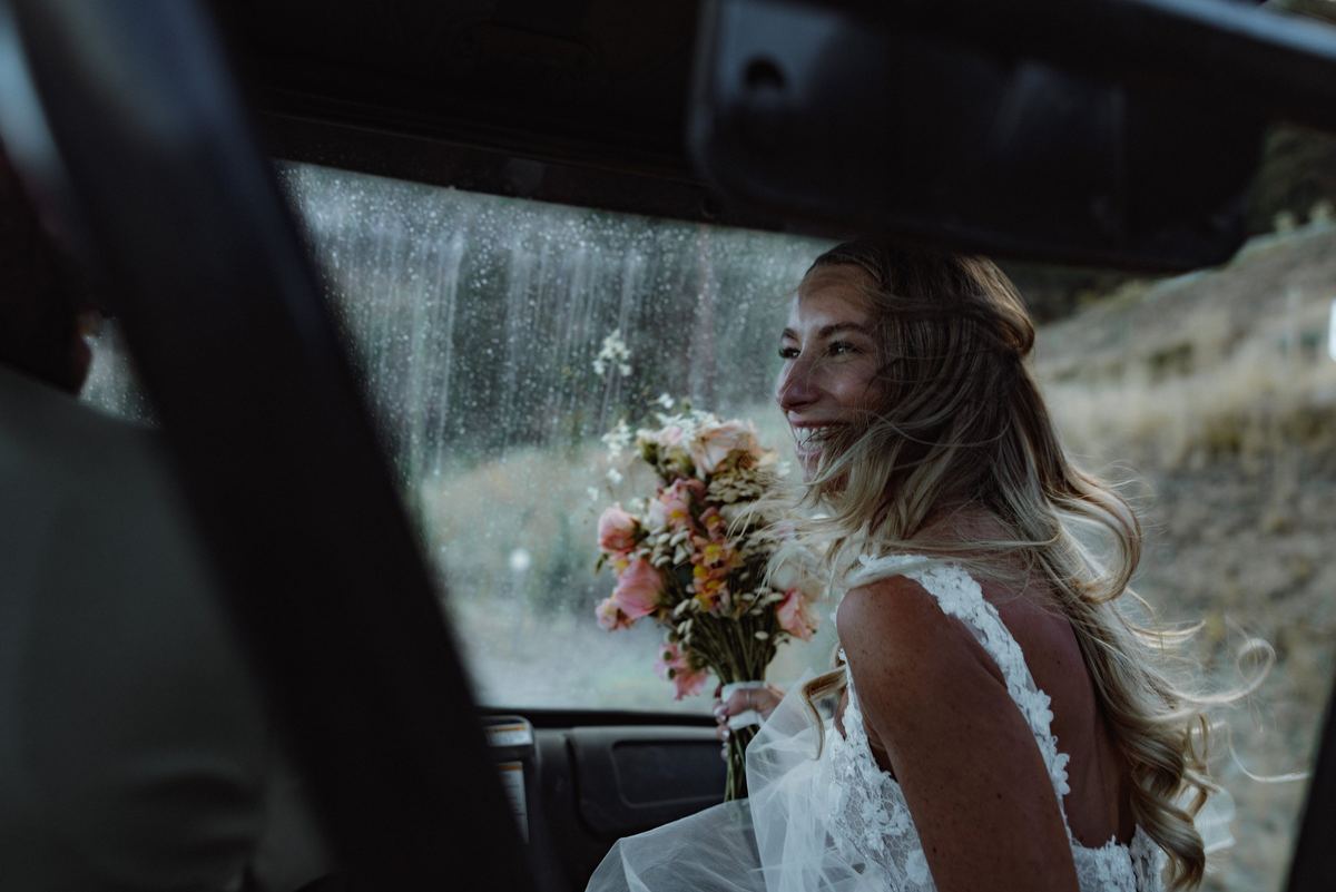 Bride in the car with her bouquet, reflected in the window