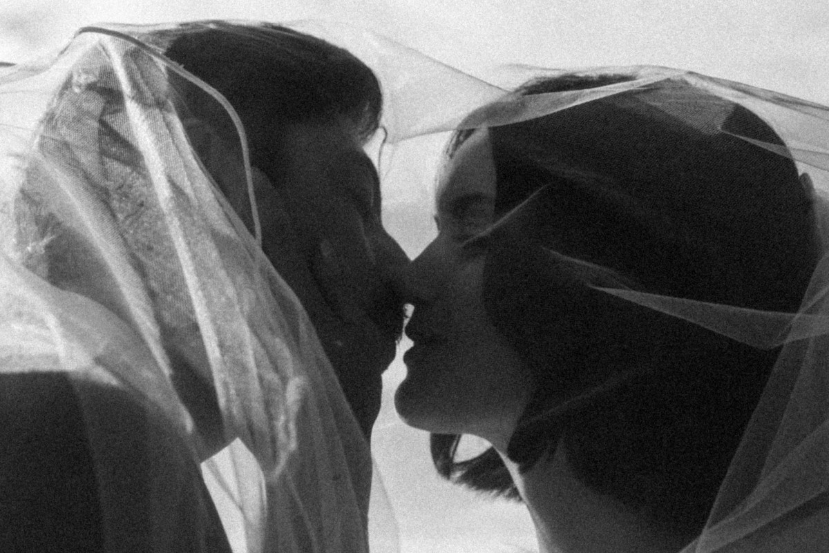 Devin and Owen kiss beneath her veil at a mountain ranch among the aspens, black and white