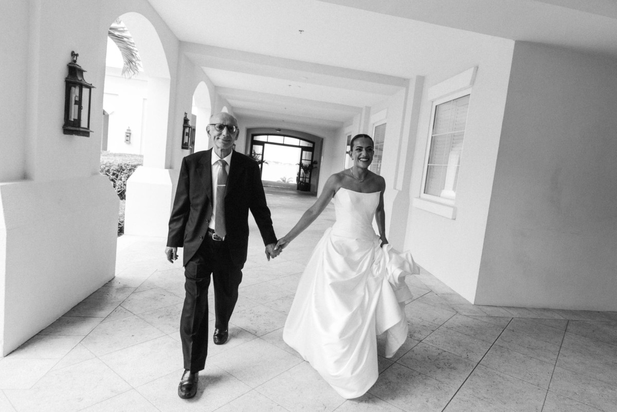 Bride and her father walking hand in hand through the colonnade at Rosewood Bermuda, black and white