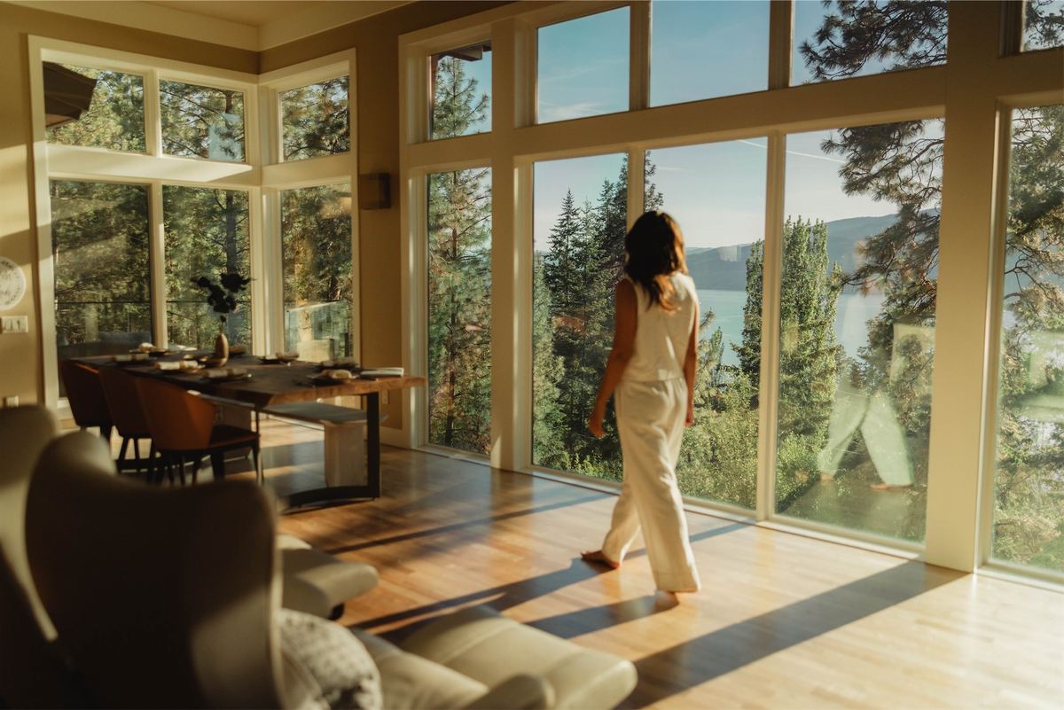 Woman in white walking past floor to ceiling windows looking over the lake