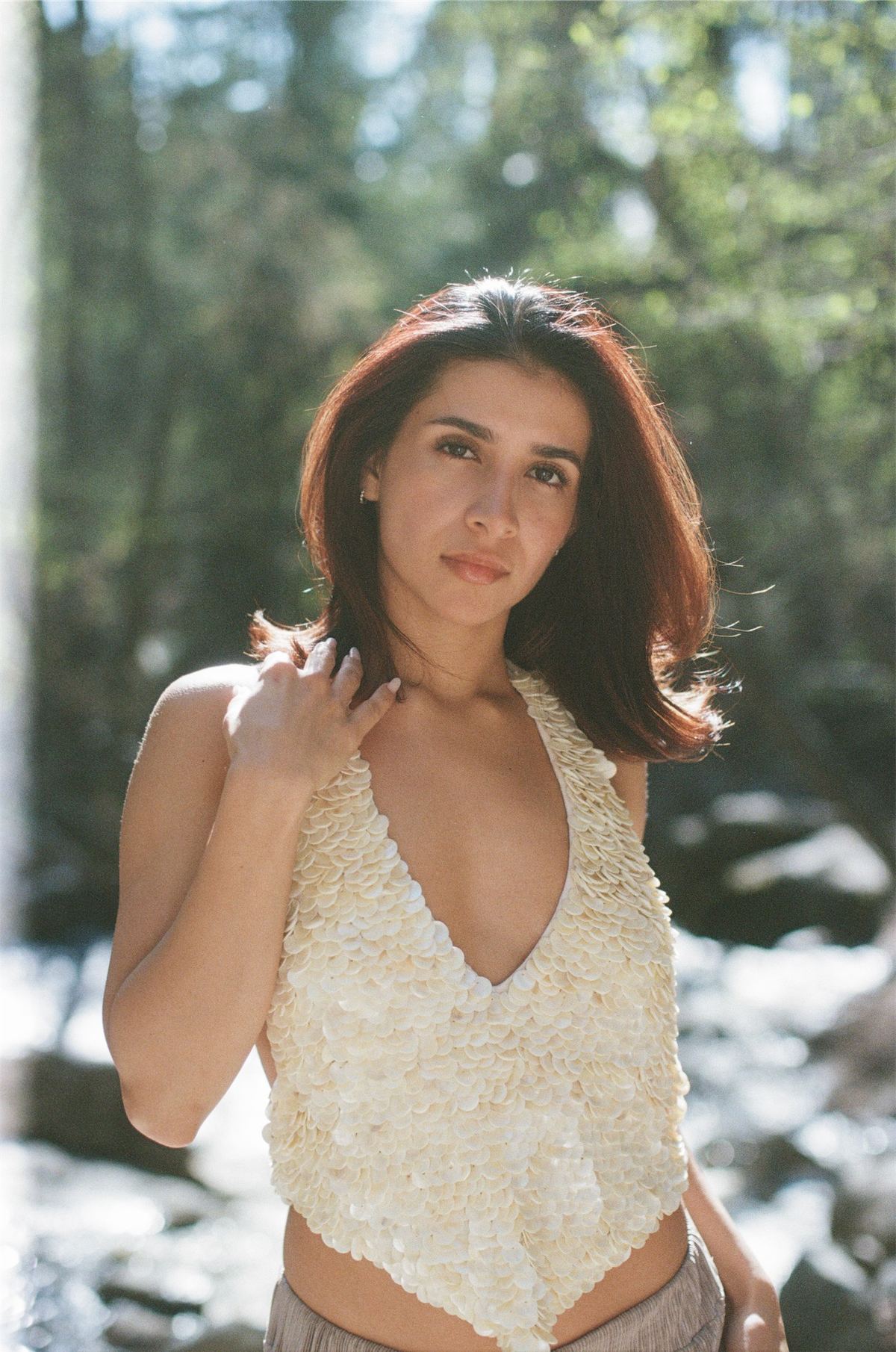 Portrait of a model in a cream crochet swimsuit surrounded by dappled forest light