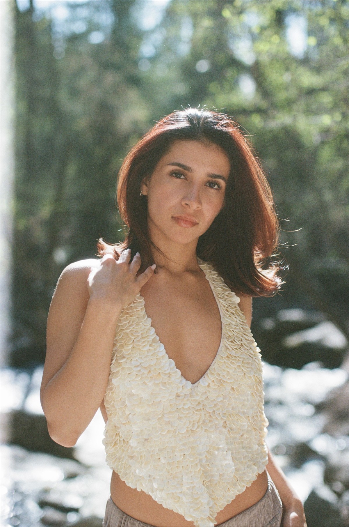 Portrait of a model in a cream crochet swimsuit surrounded by dappled forest light