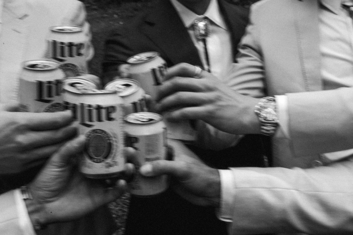 Groomsmen clink cans of Miller Lite at a mountain ranch among the aspens, black and white