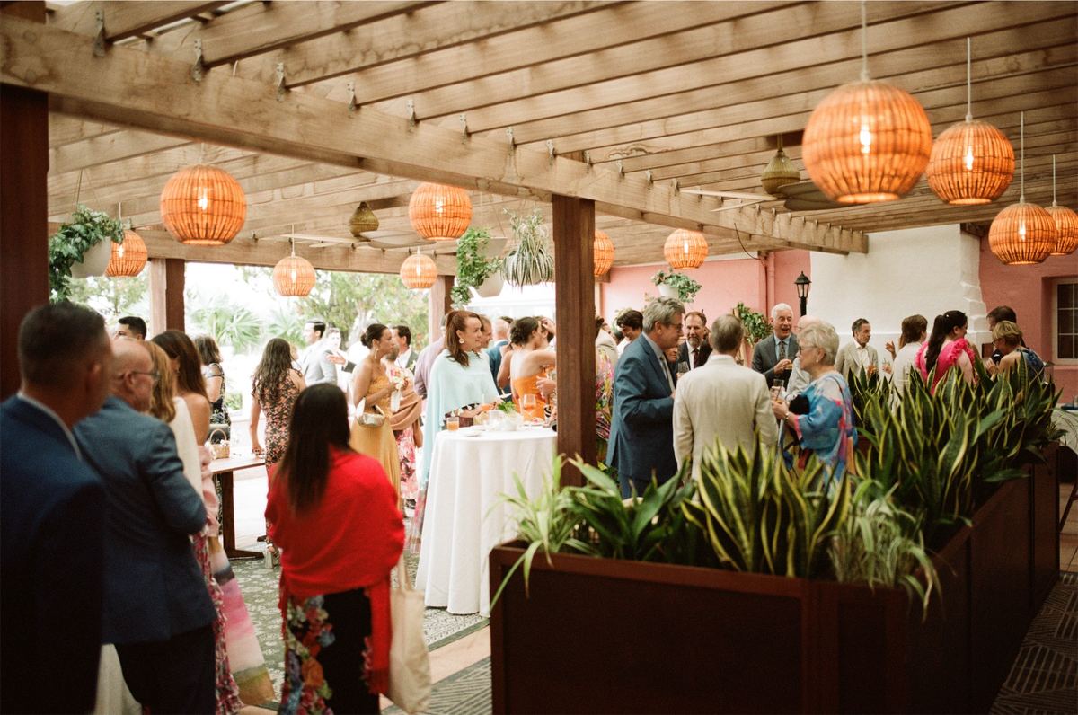 Guests mingling at cocktail hour beneath woven pendant lanterns