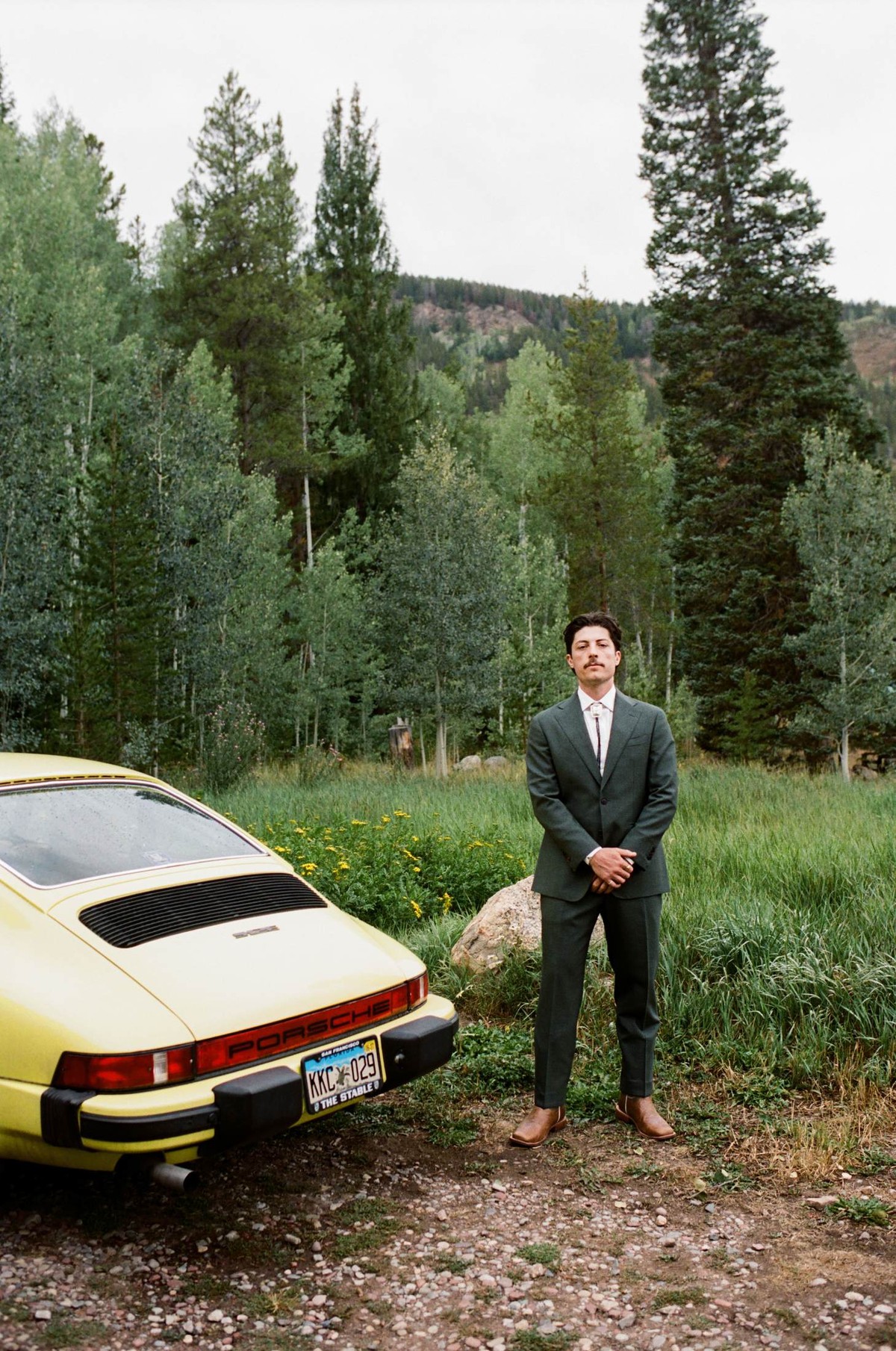 Owen stands beside a yellow vintage Porsche in the meadow, shot on film at a mountain ranch among the aspens