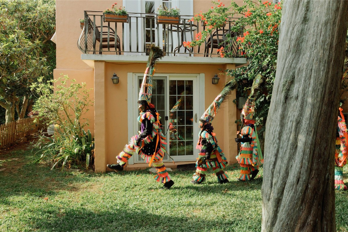 Gombey troupe dancing on the lawn outside a coral pink island house