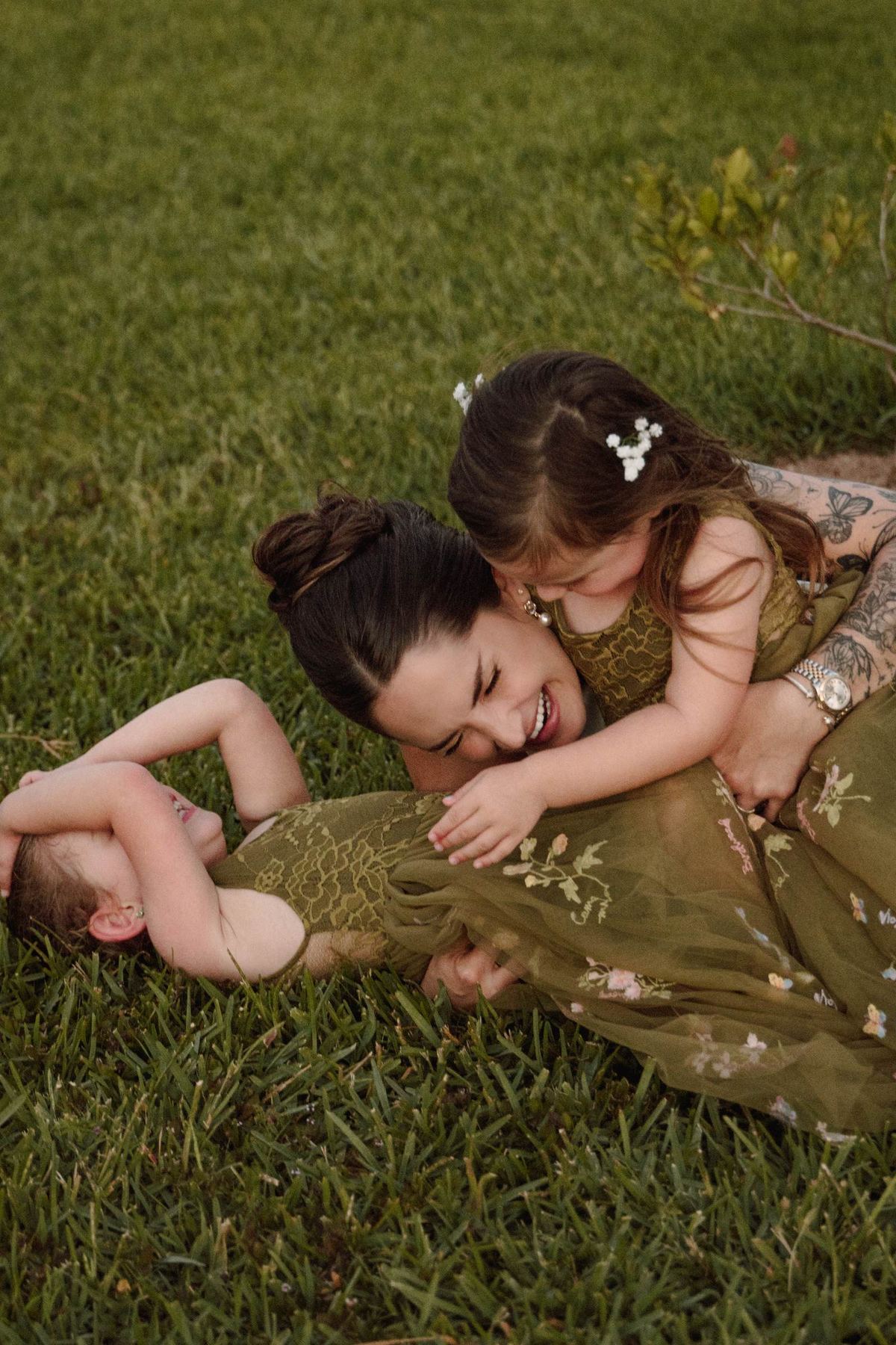 Bride lying on the grass playing with the children at her wedding
