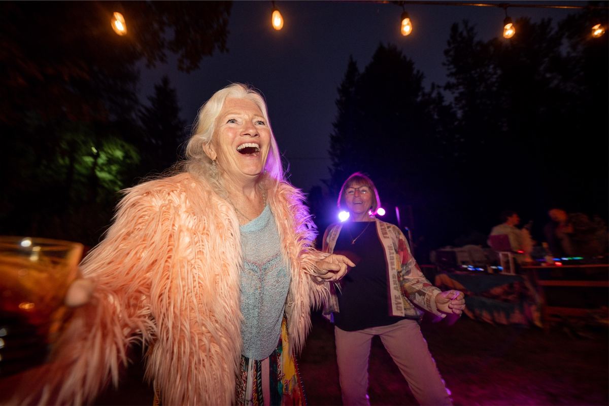 Guest in a pink faux fur coat laughing on the dance floor after dark