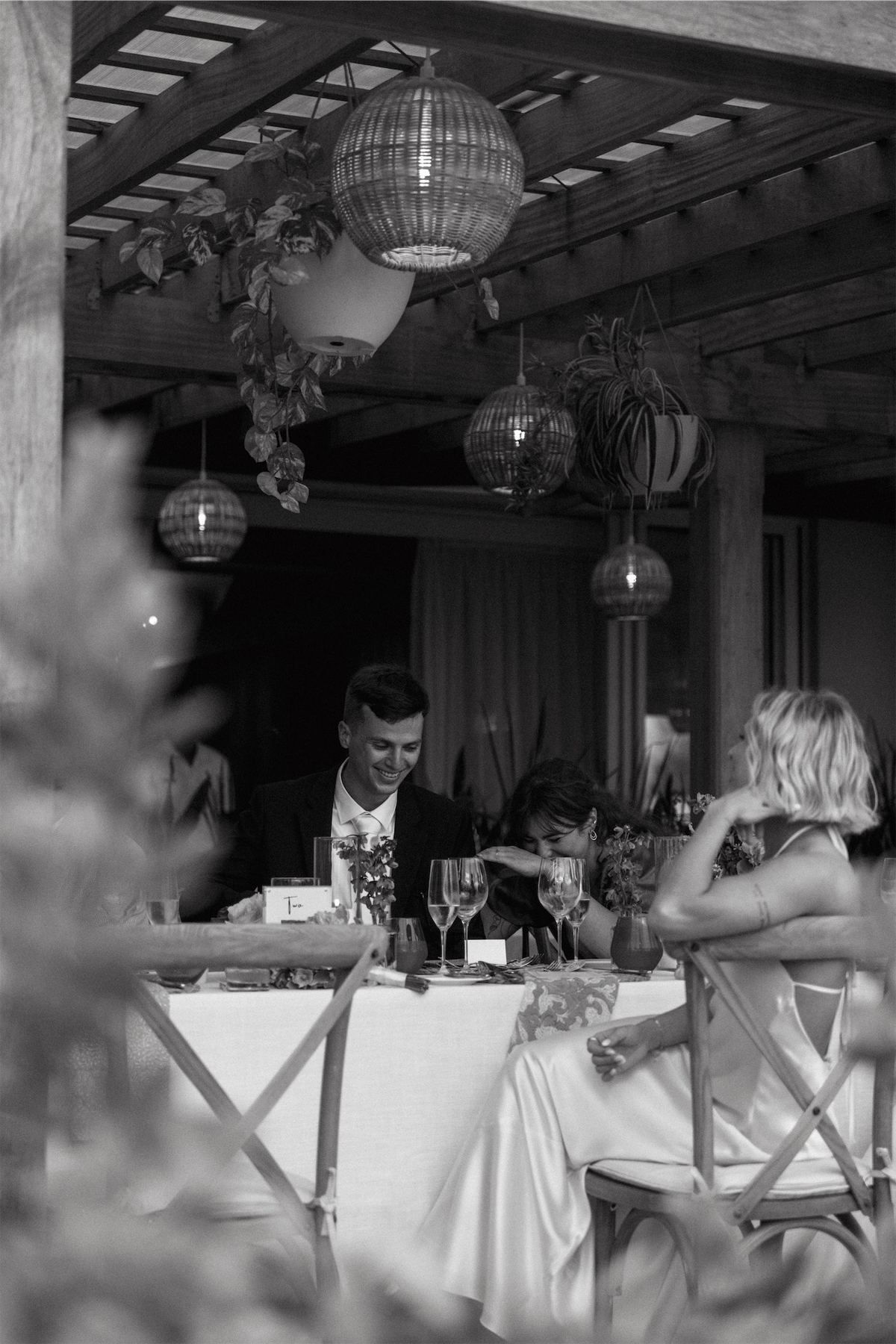 Black and white reception scene, the couple seated at the head table under lanterns