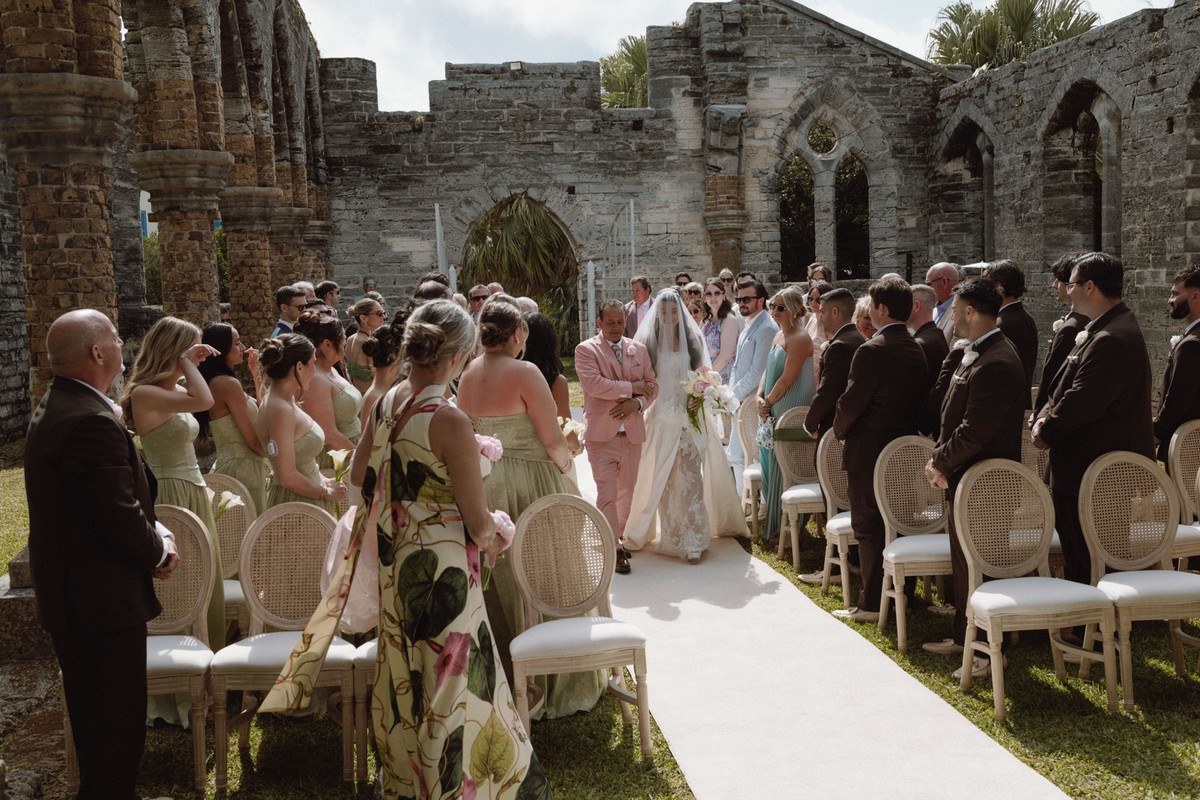Bride walking down aisle through stone ruins at Bermuda wedding ceremony
