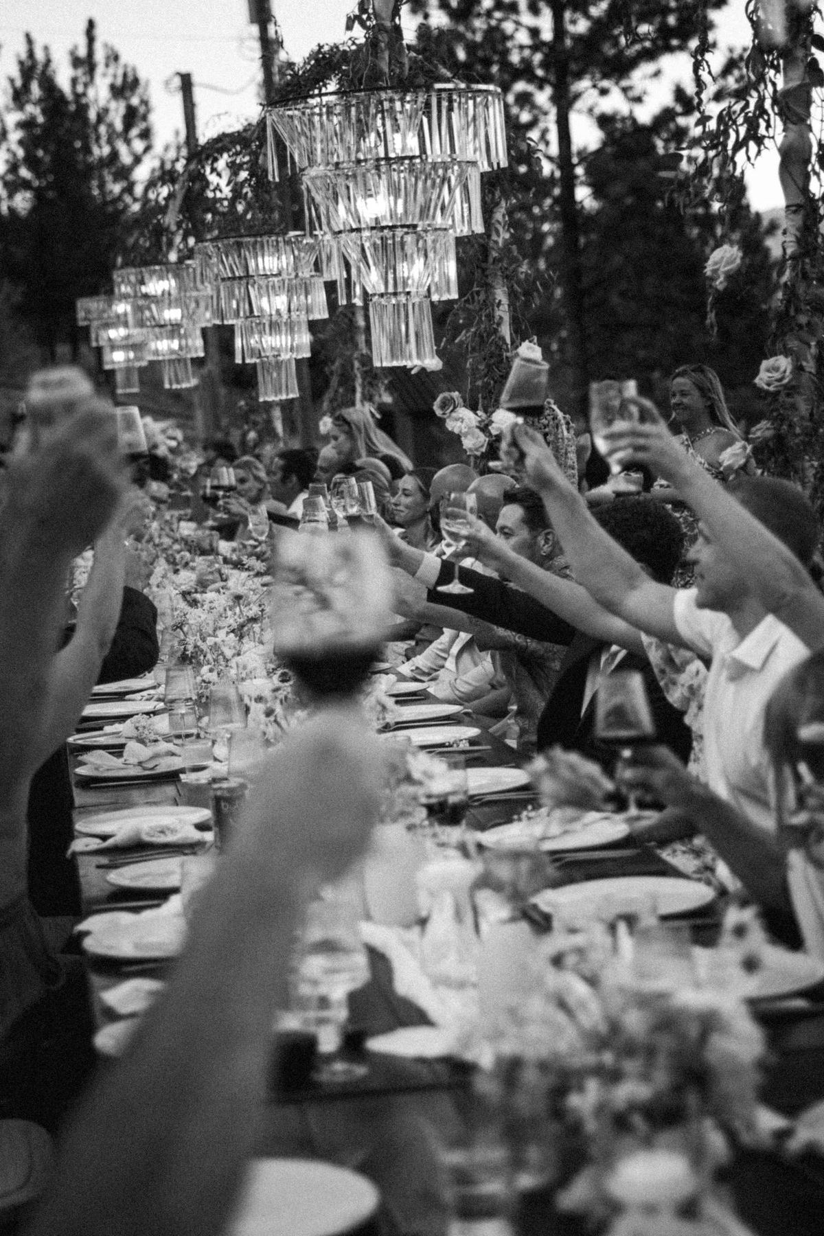 Guests raising their glasses for a toast down the long reception table