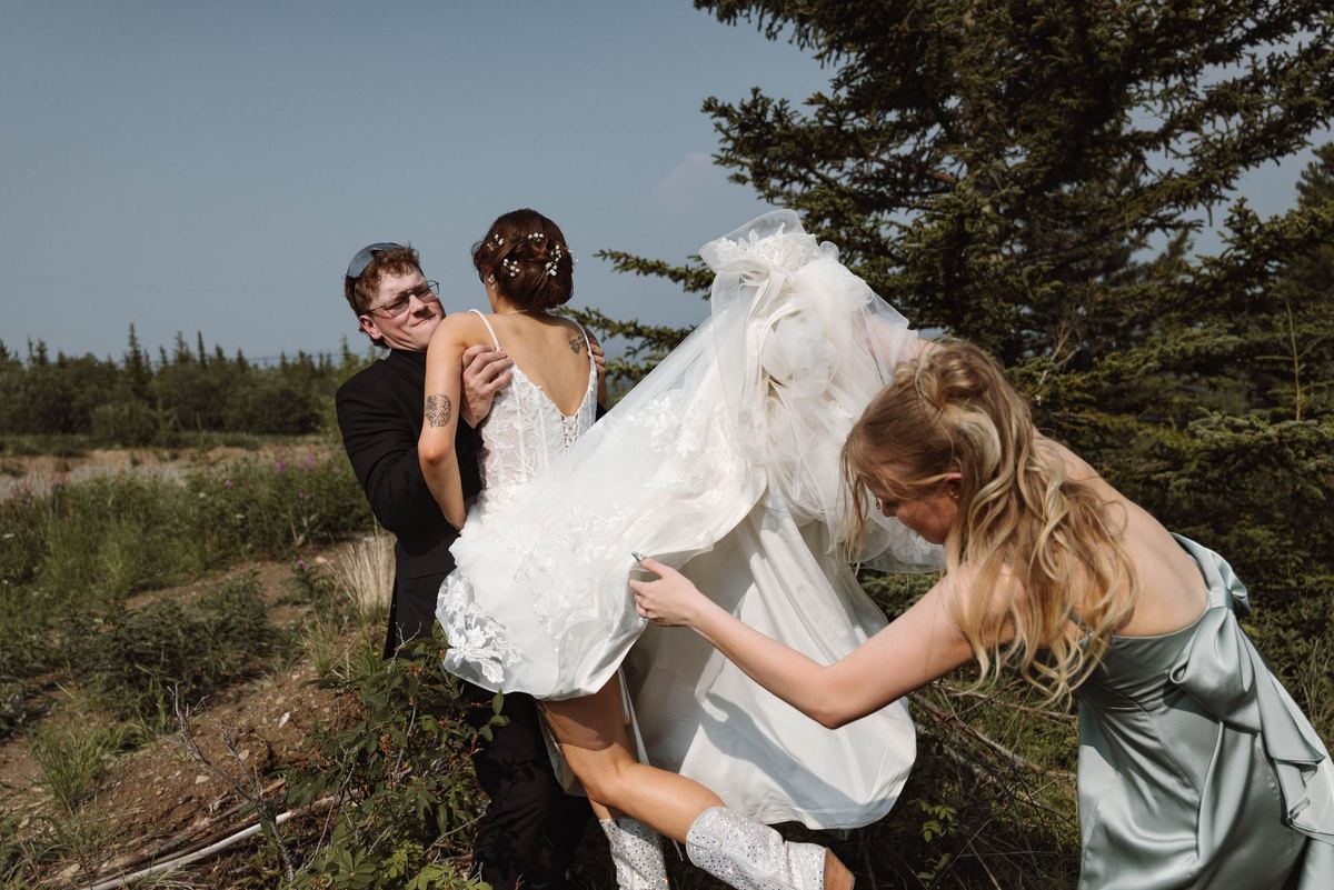 Wind catching the bride's veil as her friends laugh and help her