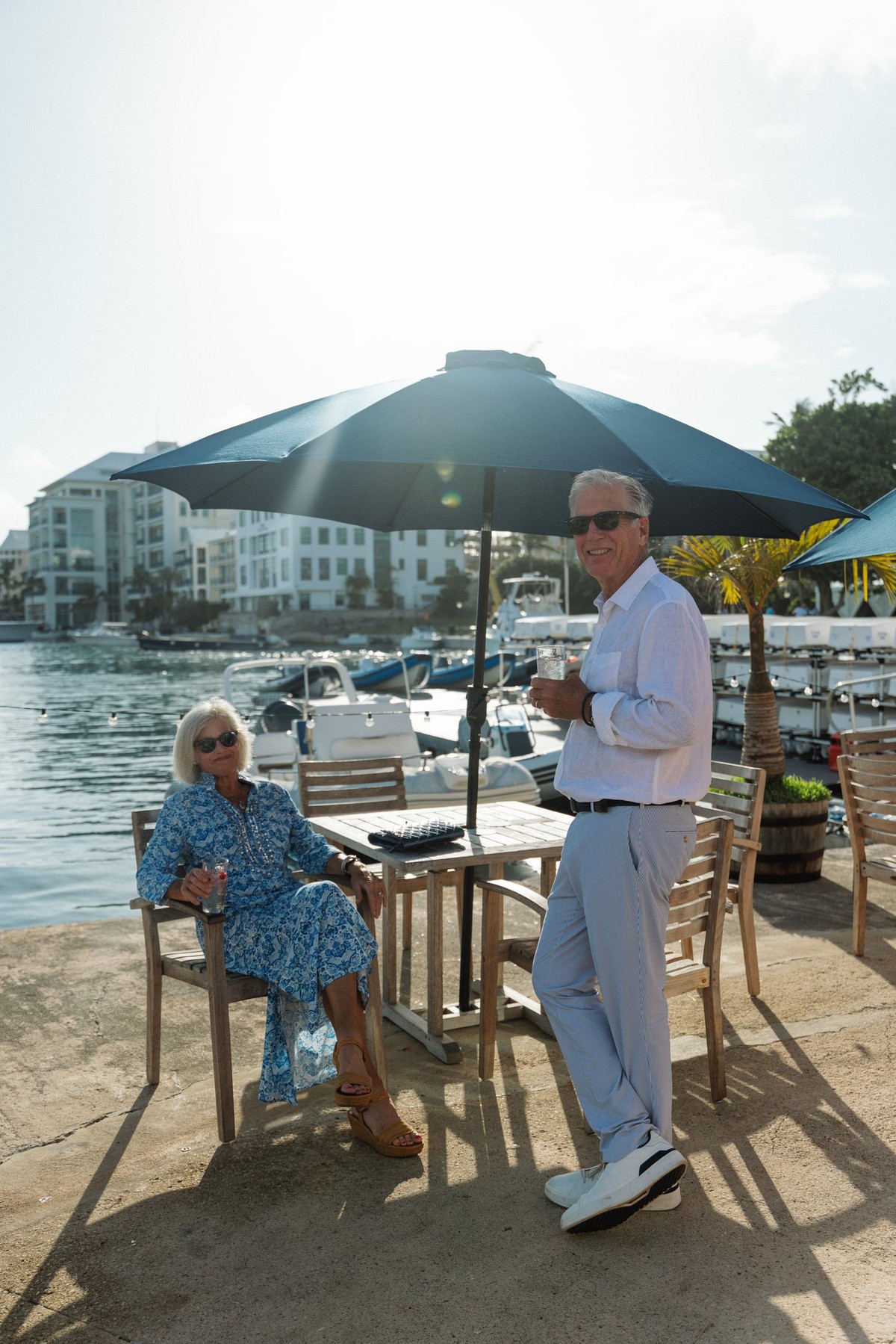 Two guests relax under a blue umbrella at the waterfront welcome party in Bermuda