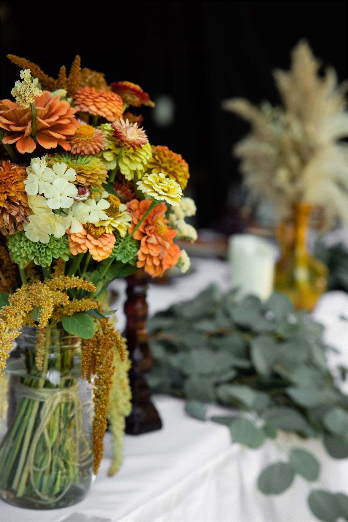 Autumn centrepiece of rust and gold blooms with eucalyptus along the reception table