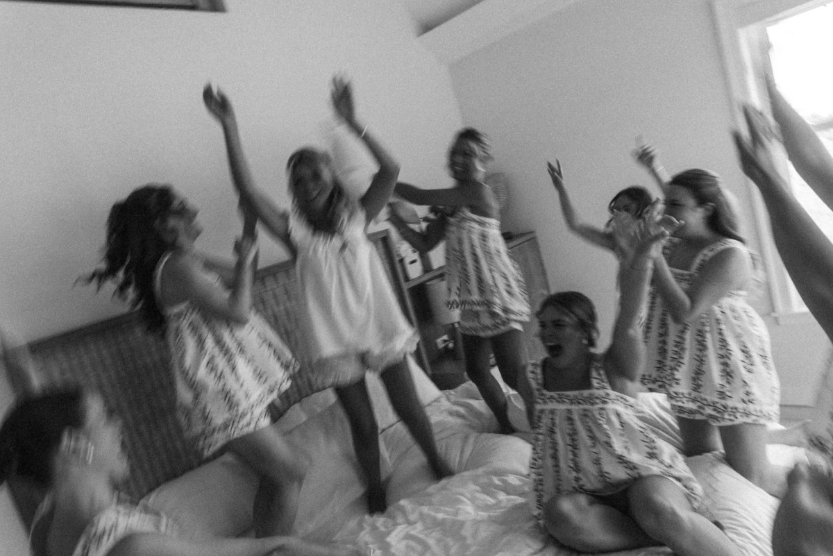 Bridesmaids jump on the bed in matching pajamas on Hawkins Island, Bermuda, black and white